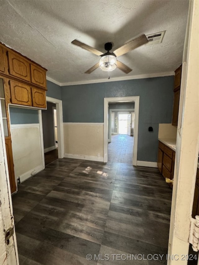 interior space with a textured ceiling, ornamental molding, dark hardwood / wood-style flooring, and ceiling fan