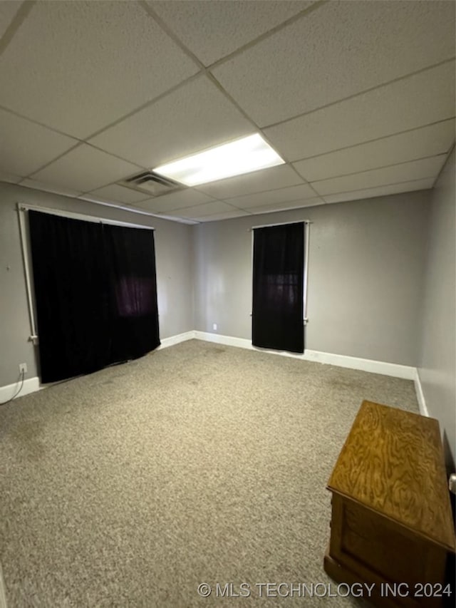 spare room with a drop ceiling and carpet flooring