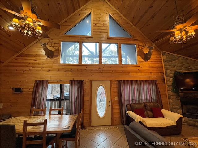 dining area with ceiling fan, wood walls, high vaulted ceiling, and a wealth of natural light