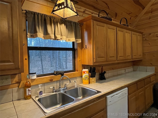 kitchen with dishwasher, tile countertops, sink, and wooden walls