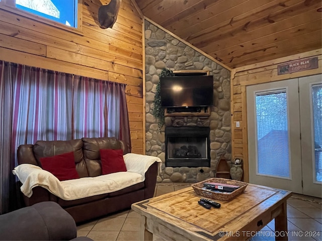 living room featuring light tile patterned flooring, wood ceiling, wood walls, a stone fireplace, and vaulted ceiling