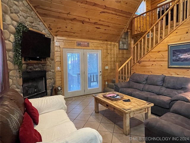 tiled living room with wooden ceiling, a stone fireplace, wooden walls, and french doors