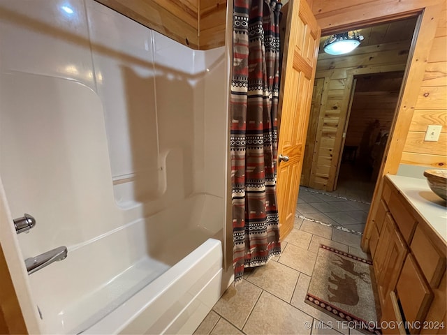 bathroom featuring tile patterned flooring, vanity, wood walls, and shower / tub combo