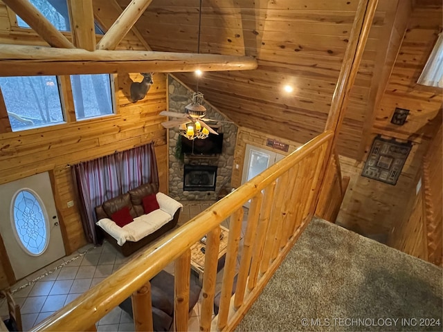 staircase featuring wood ceiling, wooden walls, high vaulted ceiling, and a stone fireplace