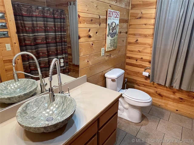 bathroom featuring tile patterned floors, wood walls, vanity, toilet, and a shower with curtain