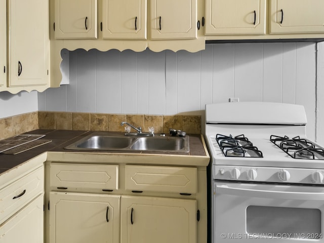 kitchen featuring cream cabinets, sink, and white gas stove