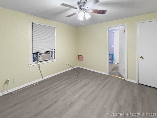 unfurnished room featuring cooling unit, light hardwood / wood-style floors, ceiling fan, and a textured ceiling