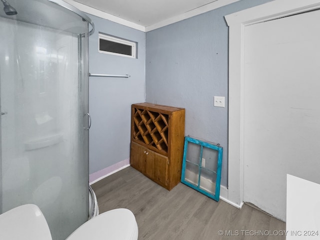 bathroom with walk in shower, crown molding, toilet, and wood-type flooring