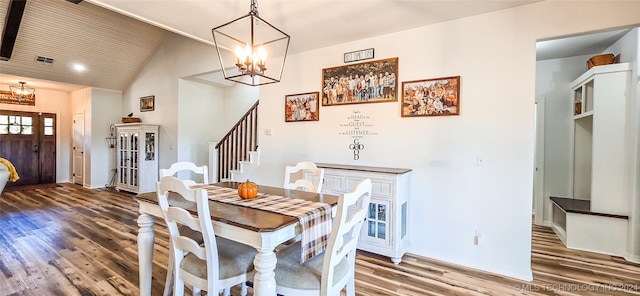 dining space with wood-type flooring, an inviting chandelier, and high vaulted ceiling