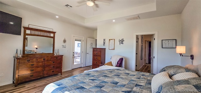 bedroom featuring light hardwood / wood-style flooring, a tray ceiling, ceiling fan, and access to outside