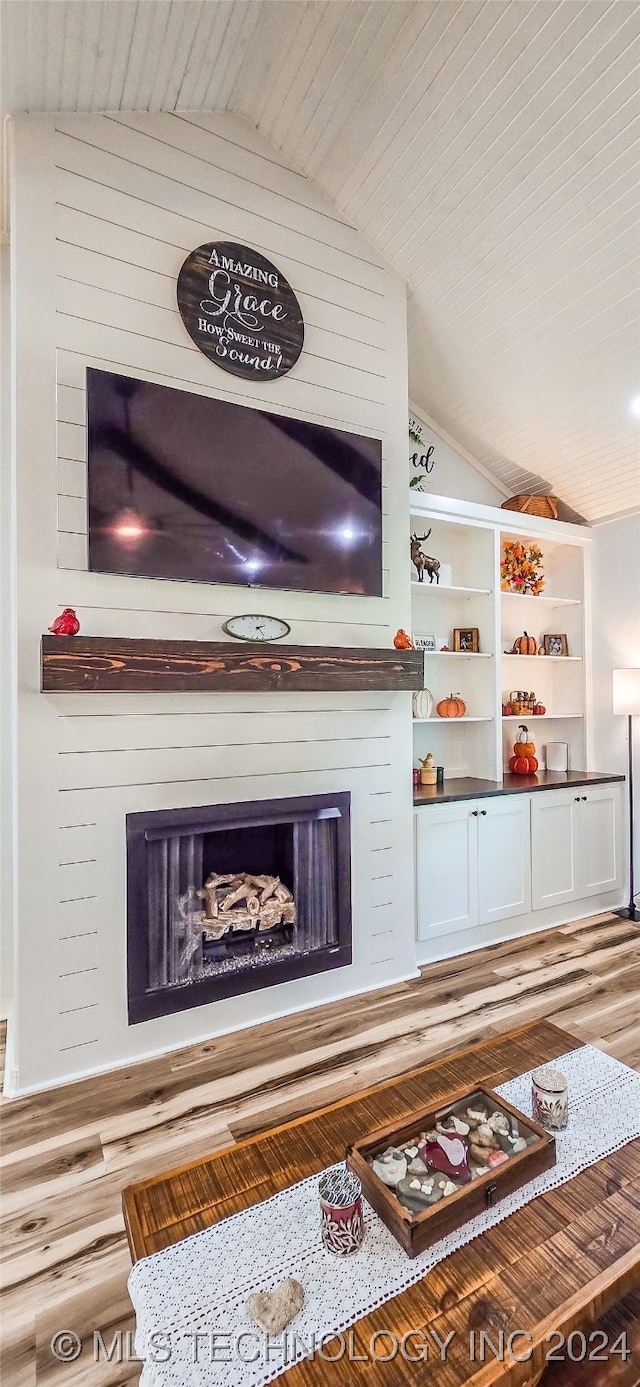 living room featuring a fireplace, built in features, hardwood / wood-style floors, and lofted ceiling