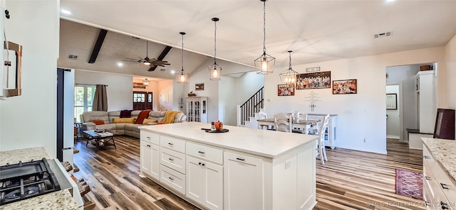 kitchen with hardwood / wood-style flooring, white cabinetry, hanging light fixtures, vaulted ceiling with beams, and ceiling fan