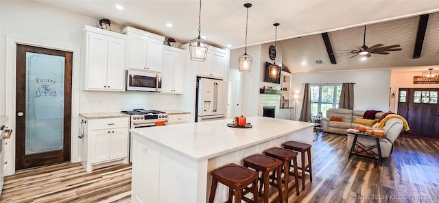 kitchen featuring premium appliances, white cabinets, a kitchen breakfast bar, and a center island