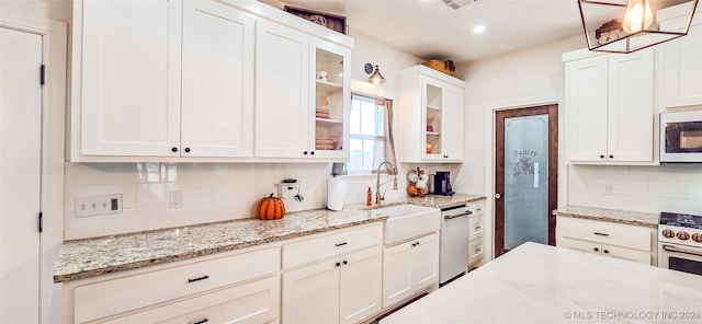 kitchen featuring pendant lighting, sink, white cabinetry, dishwashing machine, and light stone countertops