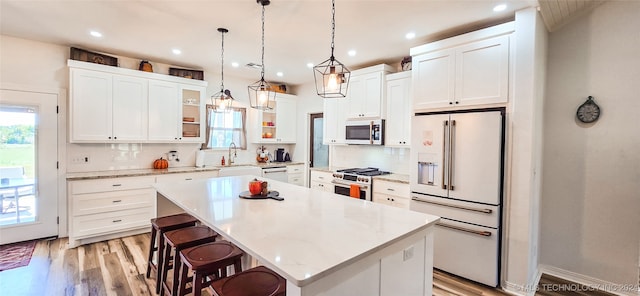 kitchen with decorative backsplash, white cabinetry, a kitchen island, and high quality appliances