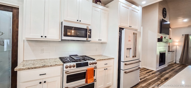 kitchen with premium appliances, white cabinetry, dark hardwood / wood-style floors, and light stone countertops