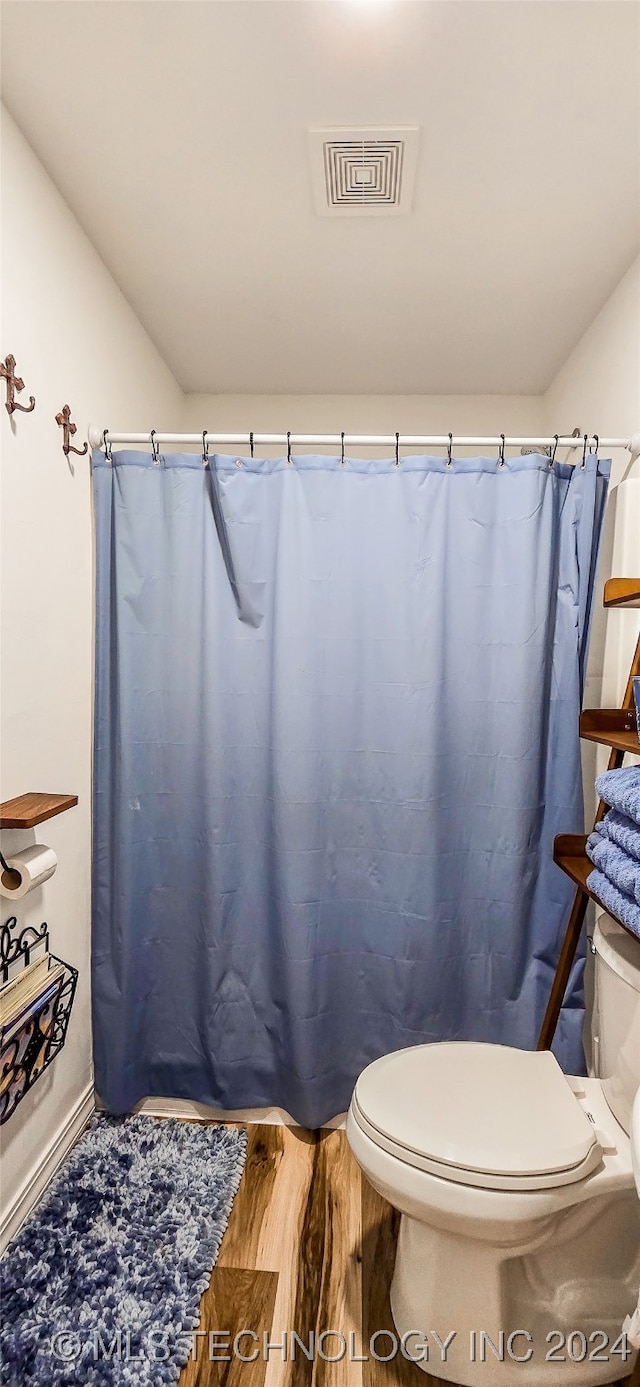 bathroom with a shower with curtain, hardwood / wood-style floors, and toilet