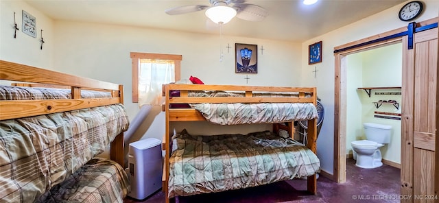 bedroom with ceiling fan, connected bathroom, and a barn door