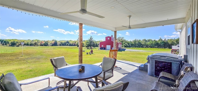 sunroom featuring ceiling fan and a rural view