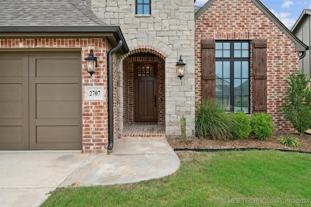 doorway to property with a lawn and a garage