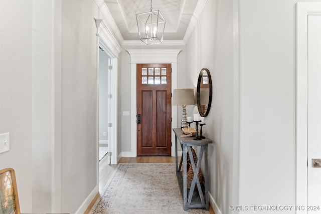 entryway with an inviting chandelier, light hardwood / wood-style floors, and ornamental molding