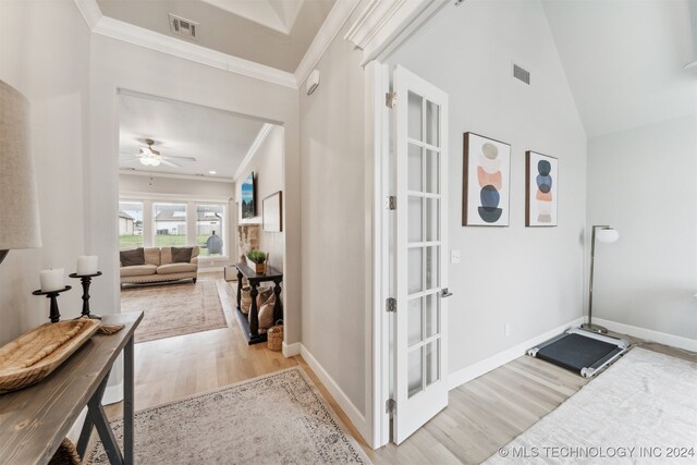 hallway with vaulted ceiling, light hardwood / wood-style floors, and crown molding