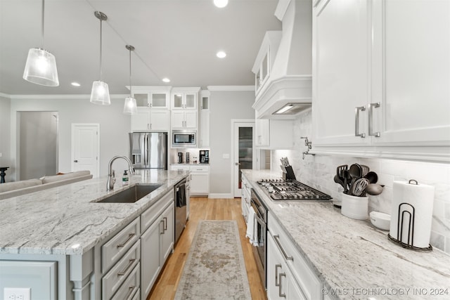 kitchen with sink, white cabinets, stainless steel appliances, a center island with sink, and decorative light fixtures