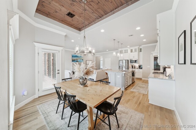 dining area featuring wood ceiling, crown molding, a tray ceiling, light hardwood / wood-style flooring, and a chandelier