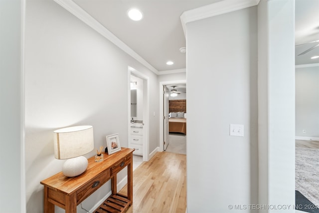 hallway with light wood-type flooring and crown molding