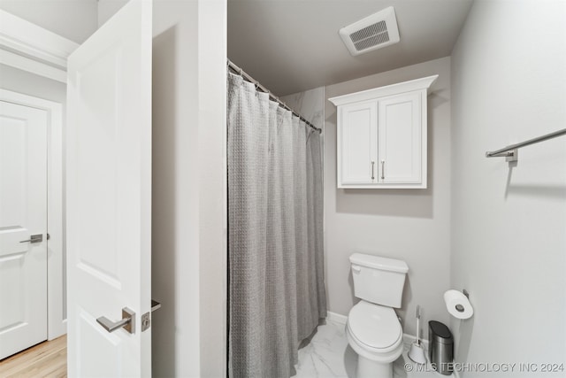 bathroom featuring hardwood / wood-style flooring, toilet, and curtained shower