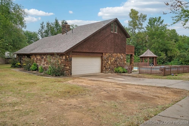 view of home's exterior featuring a garage, a gazebo, and a lawn