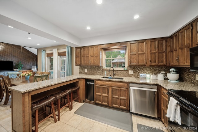 kitchen with sink, kitchen peninsula, backsplash, black appliances, and light stone countertops