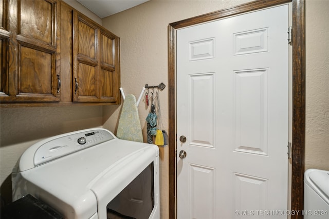 laundry area featuring washing machine and clothes dryer and cabinets