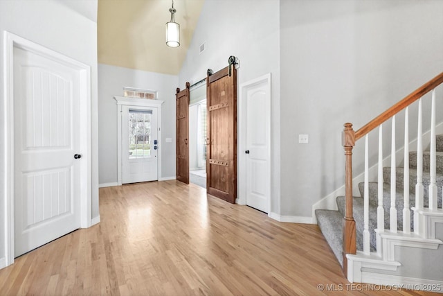 foyer with a barn door, light hardwood / wood-style flooring, and a high ceiling