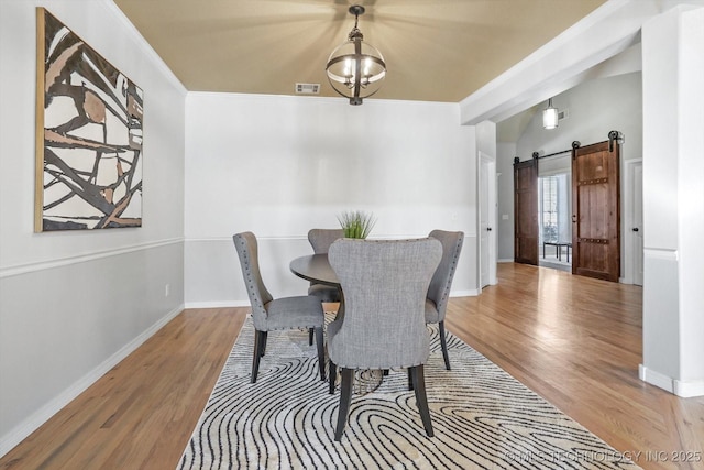 dining space featuring crown molding, wood-type flooring, and a barn door