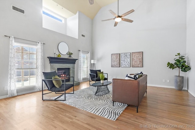 living room with ceiling fan, wood-type flooring, and a high ceiling