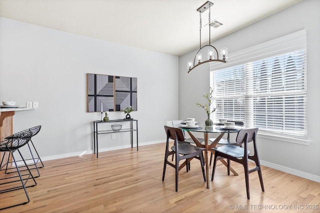 dining space with light hardwood / wood-style floors and a chandelier