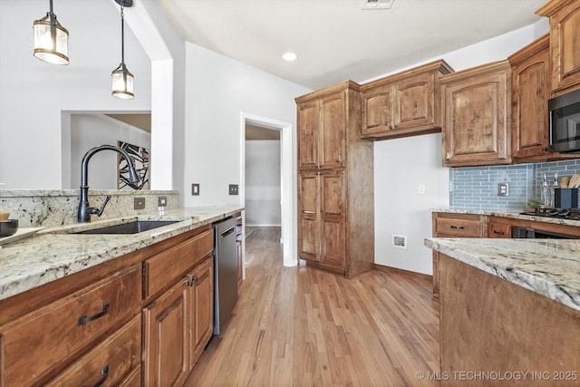 kitchen featuring sink, light stone counters, backsplash, light hardwood / wood-style floors, and black appliances