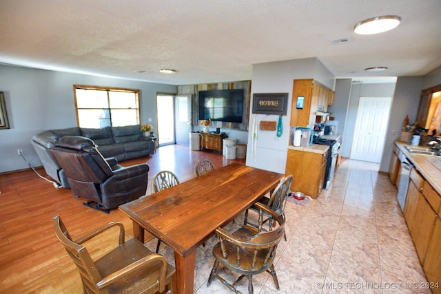 dining space with a textured ceiling, sink, and light hardwood / wood-style floors