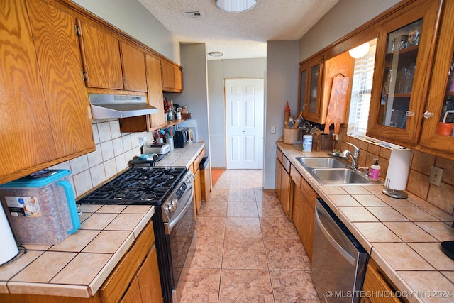 kitchen featuring tile counters, sink, stainless steel appliances, and tasteful backsplash