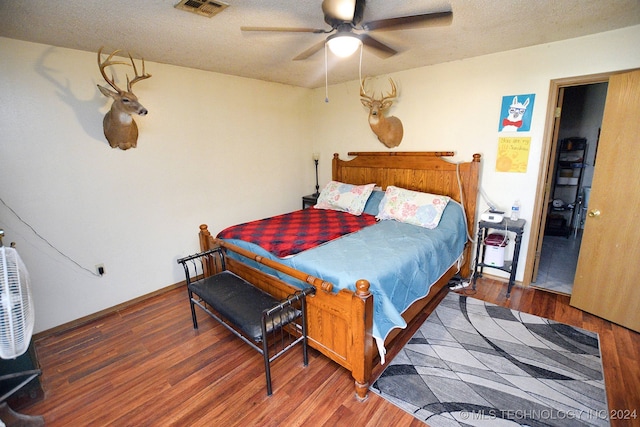 bedroom featuring ceiling fan, a textured ceiling, and dark hardwood / wood-style floors