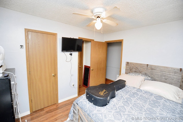 bedroom featuring light hardwood / wood-style floors, ceiling fan, and a textured ceiling