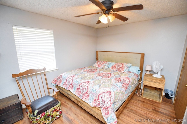 bedroom featuring ceiling fan, hardwood / wood-style floors, and a textured ceiling