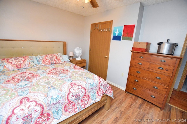 bedroom with a textured ceiling, light hardwood / wood-style floors, and ceiling fan