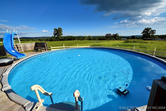 view of pool with a lawn and a water slide