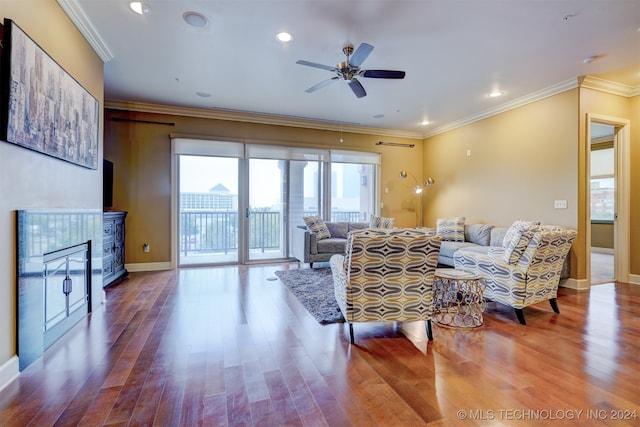 living room featuring ornamental molding, wood-type flooring, ceiling fan, and a fireplace