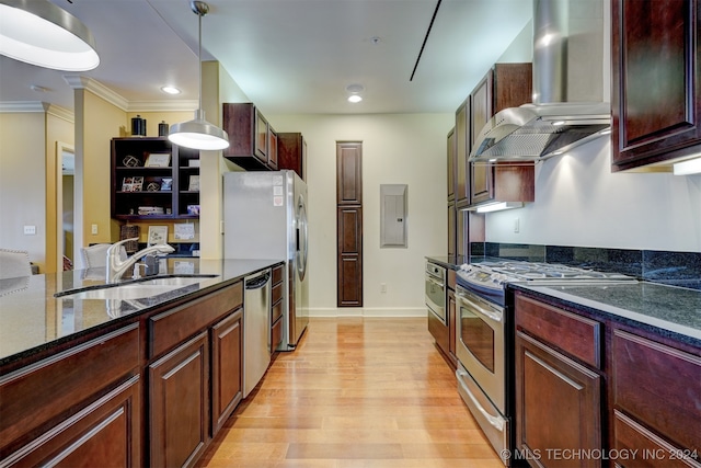 kitchen with sink, decorative light fixtures, wall chimney range hood, appliances with stainless steel finishes, and light wood-type flooring