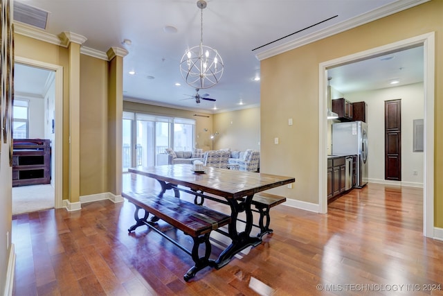 dining space with wood-type flooring, ceiling fan with notable chandelier, and ornamental molding