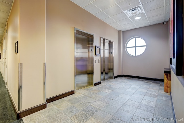 interior space with a drop ceiling and elevator