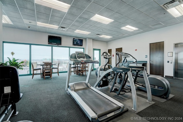 workout area with elevator, a paneled ceiling, and dark carpet